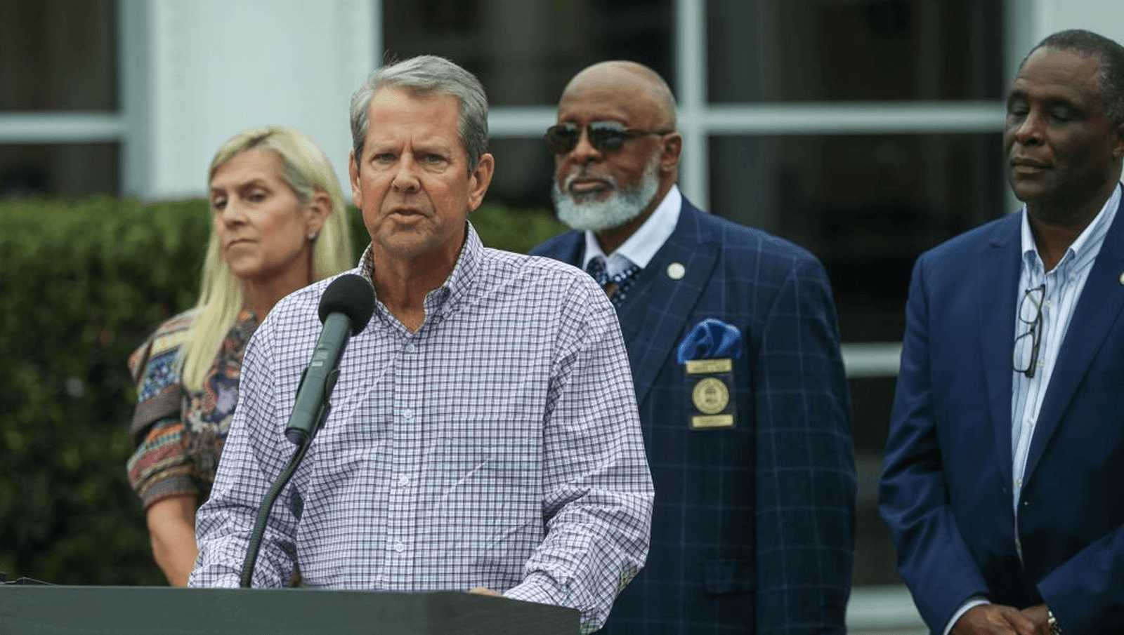 a man is giving a speech on a stage with his guards and his assistant
