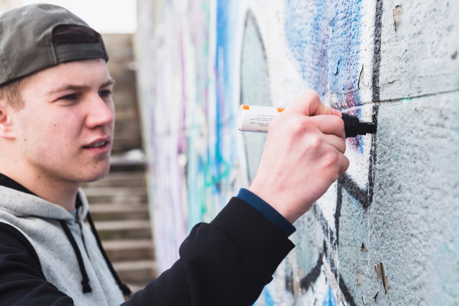 A young boy sketching on a street wall